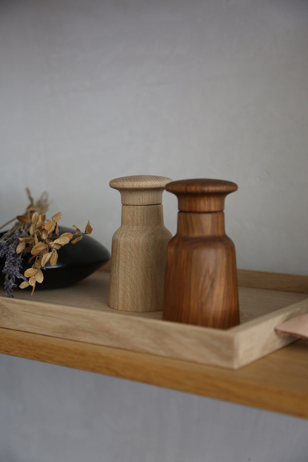 Salt and pepper shakers in oak and teak on a wooden tray