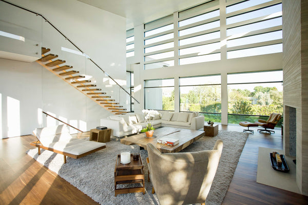 The living room at Maison Meadowlark with floor to ceiling windows and an exposed wooden staircase