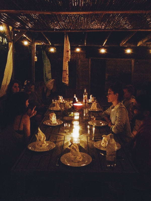 Friends gathered around a candle lit dinner in a outdoor patio of Maison Ocean, a beach house in the Hamptons